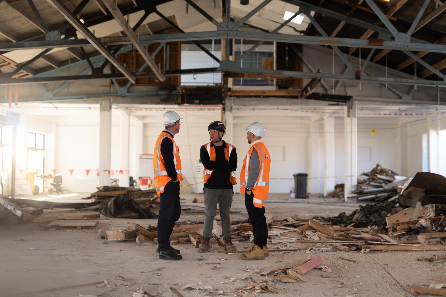A group of construction workers wearing high‑visibility vests standing inside a partially stripped commercial building