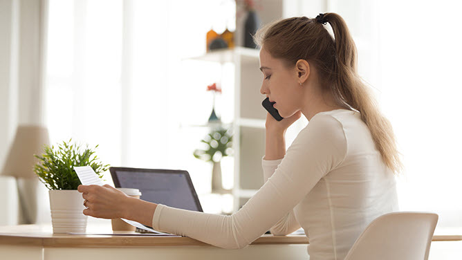 Young woman on phone sitting at her laptop