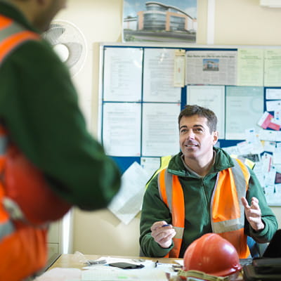 Two male construction workers talking in an office