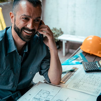 Male construction worker talking on phone at work desk