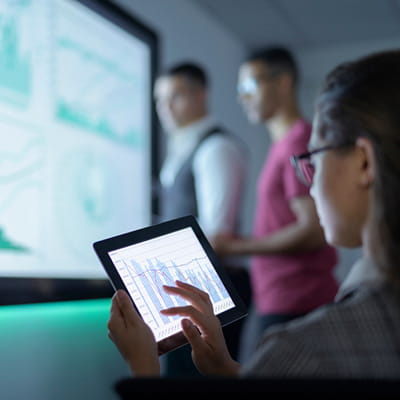 Rear view of woman using a tablet device while seated during work presentation