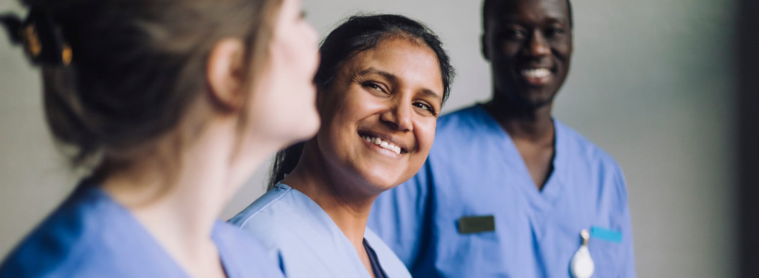 Headshot of three healthcare workers smiling at each other