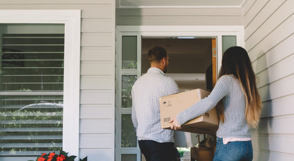 Home and contents insurance banner - young couple moving their contents into their home