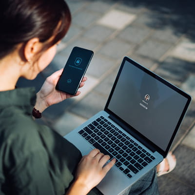 Woman performing MFA with her mobile phone and laptop